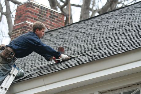 A man is working on the roof of a house.