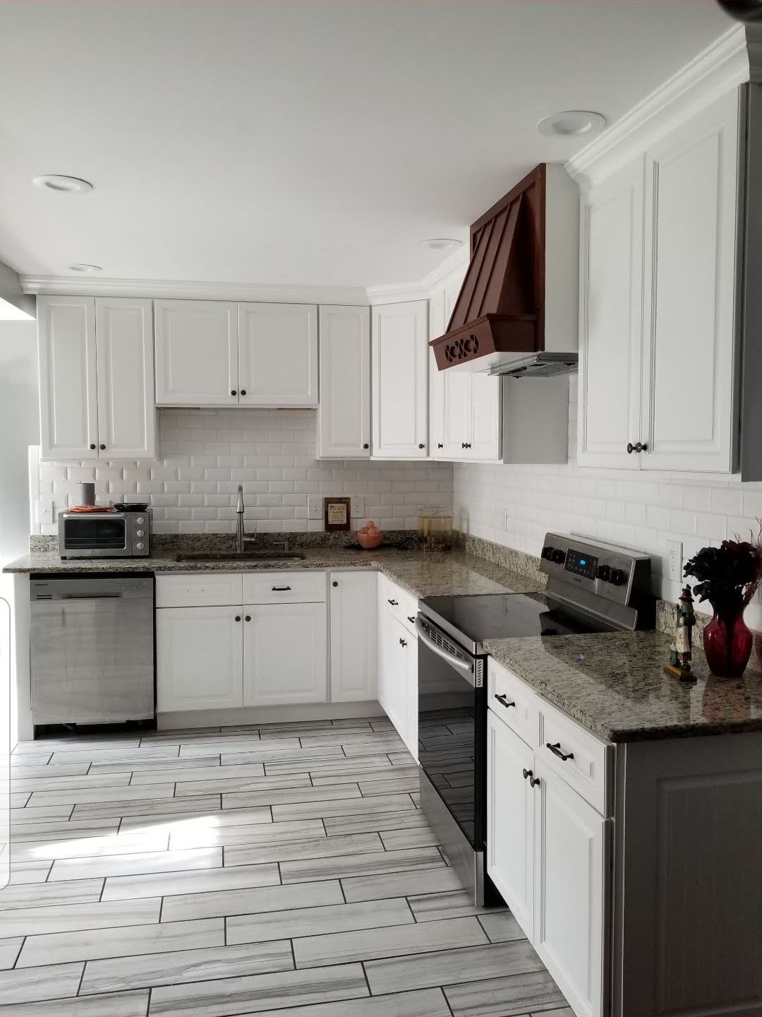 A kitchen with white cabinets , granite counter tops , stainless steel appliances and a stove.