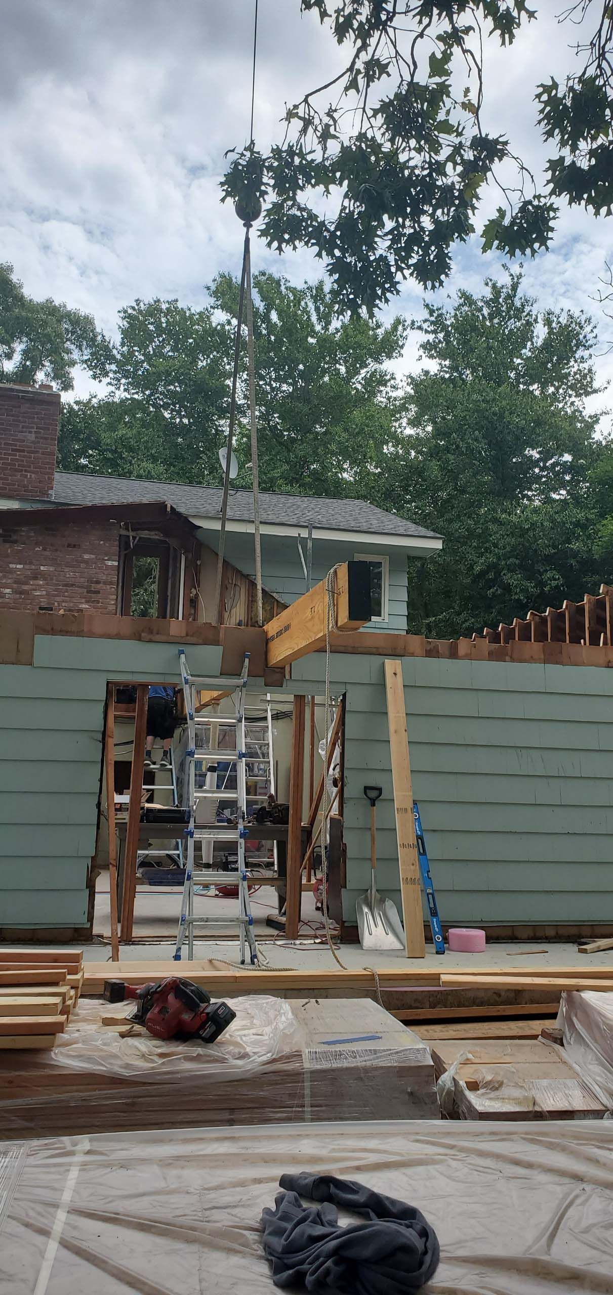 A man is standing on a ladder in front of a house under construction.