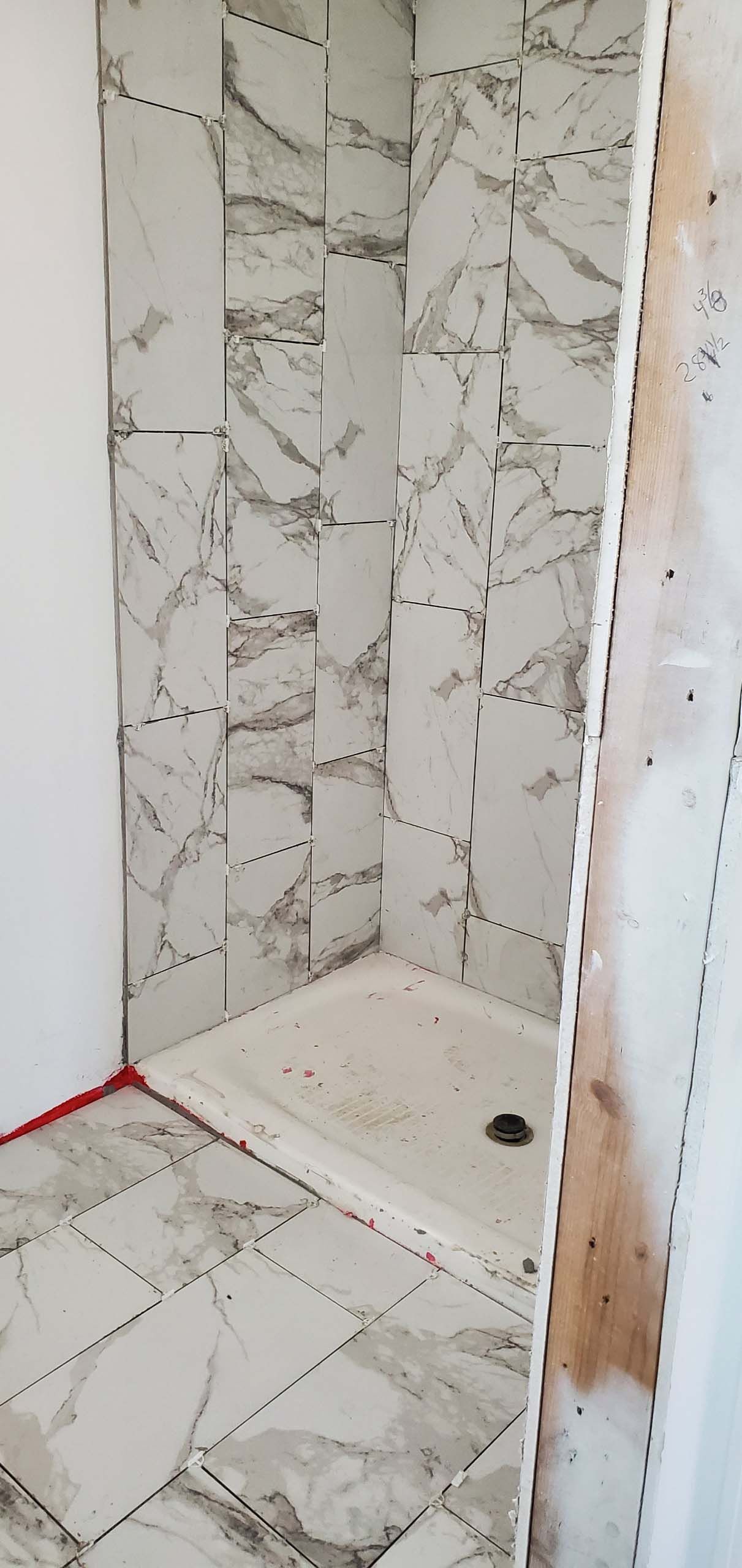 A bathroom with marble tiles and a shower stall under construction.