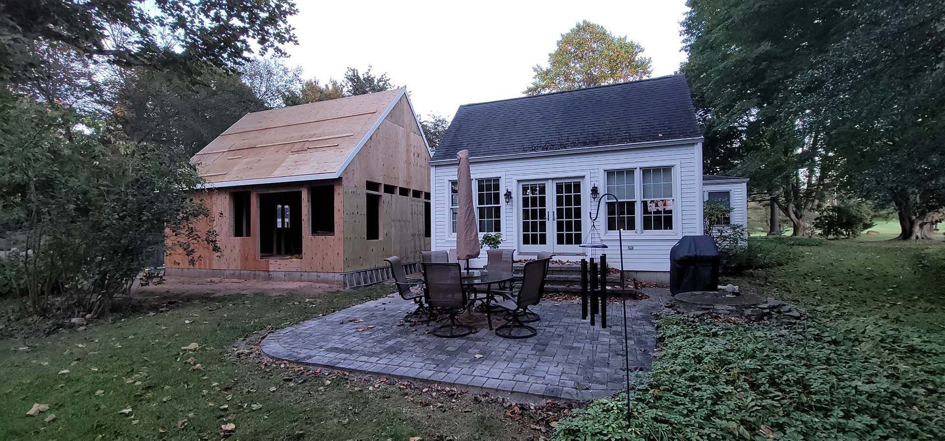 A house with a patio in front of it and a shed in the backyard.
