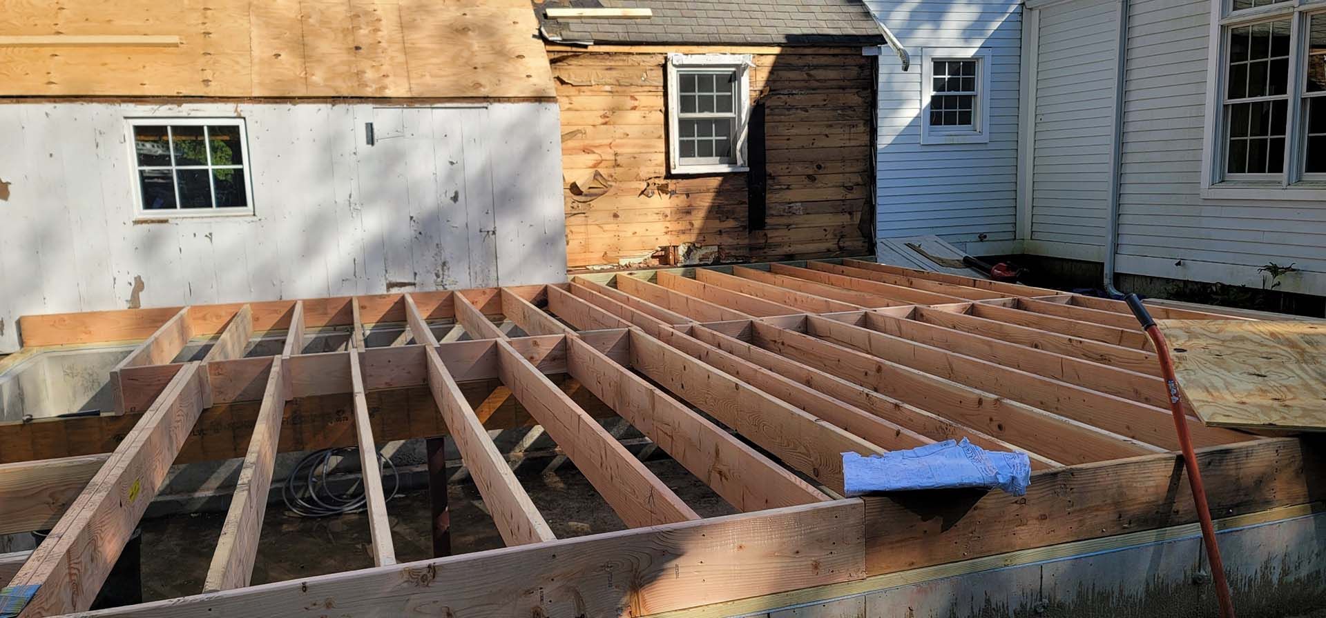 A wooden deck is being built in front of a house.