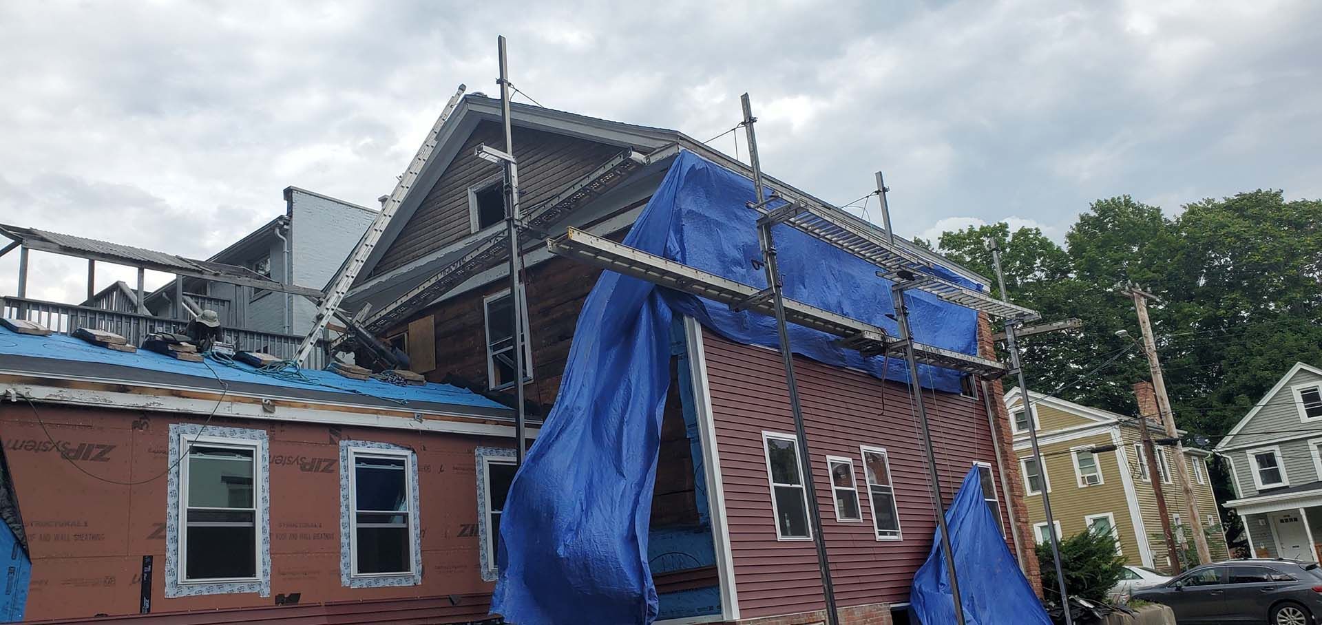 A house with a blue tarp on the roof is being remodeled.