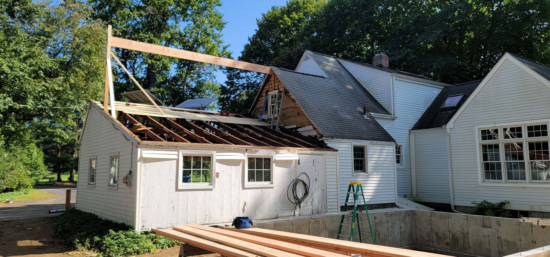 A white house with a black roof is being remodeled.