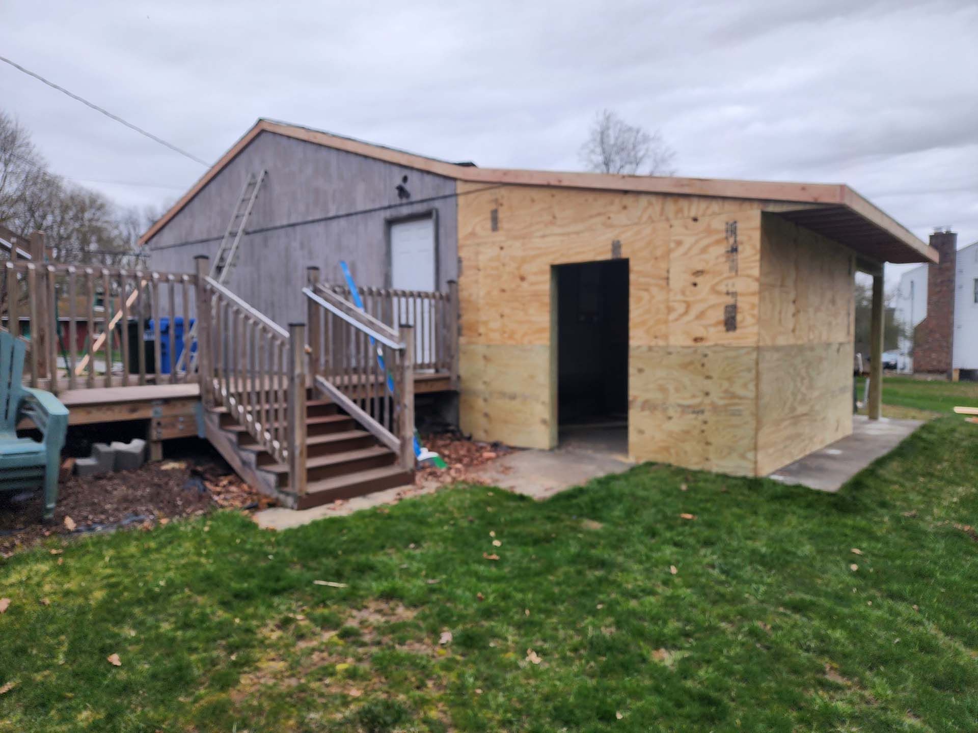 A wooden shed is being built in the backyard of a house.
