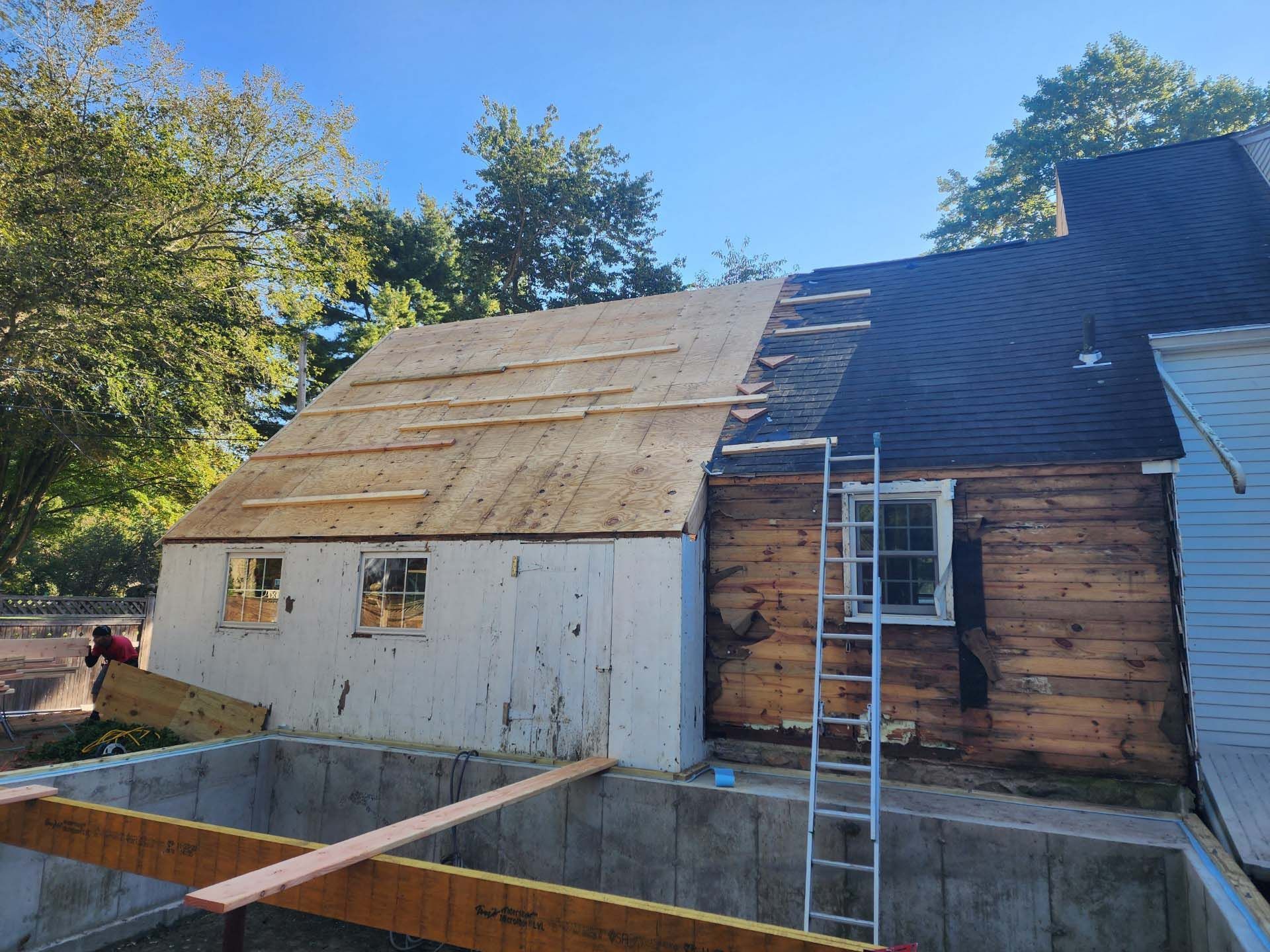 A house with a ladder on the side of it is being remodeled.
