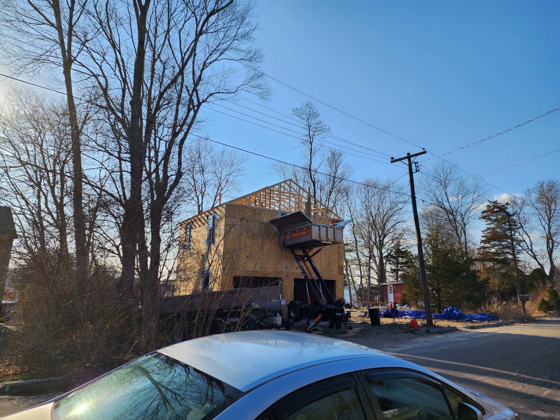 A white car is parked in front of a building under construction.