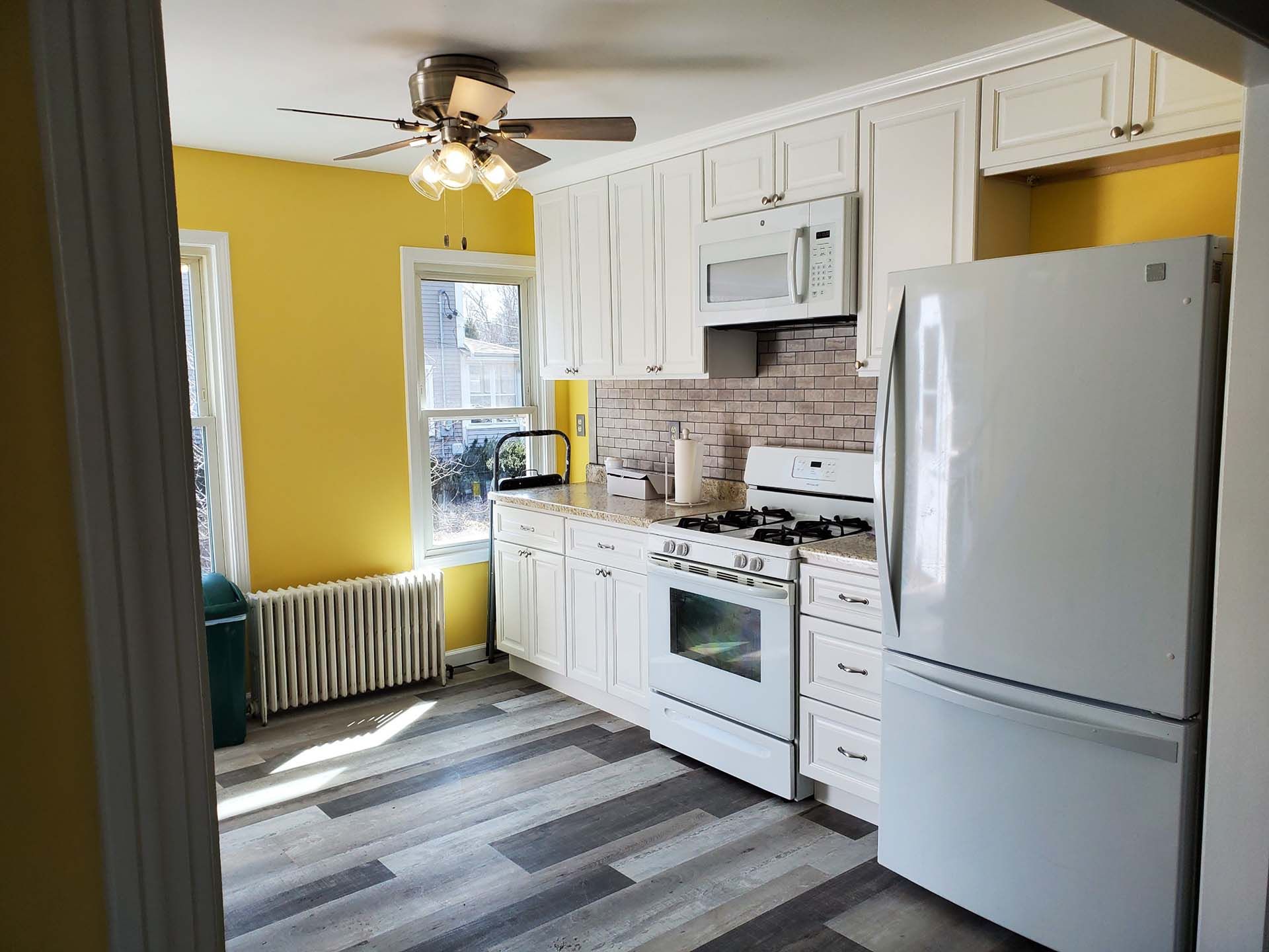 A kitchen with a refrigerator , stove , microwave and ceiling fan.