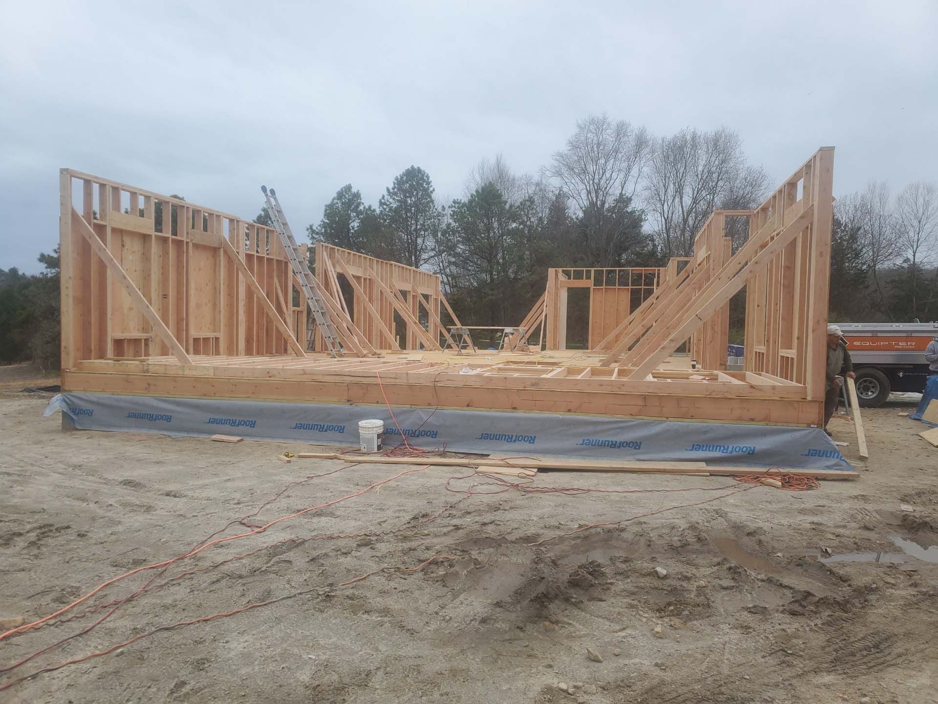 A large wooden structure is being built in a dirt field.