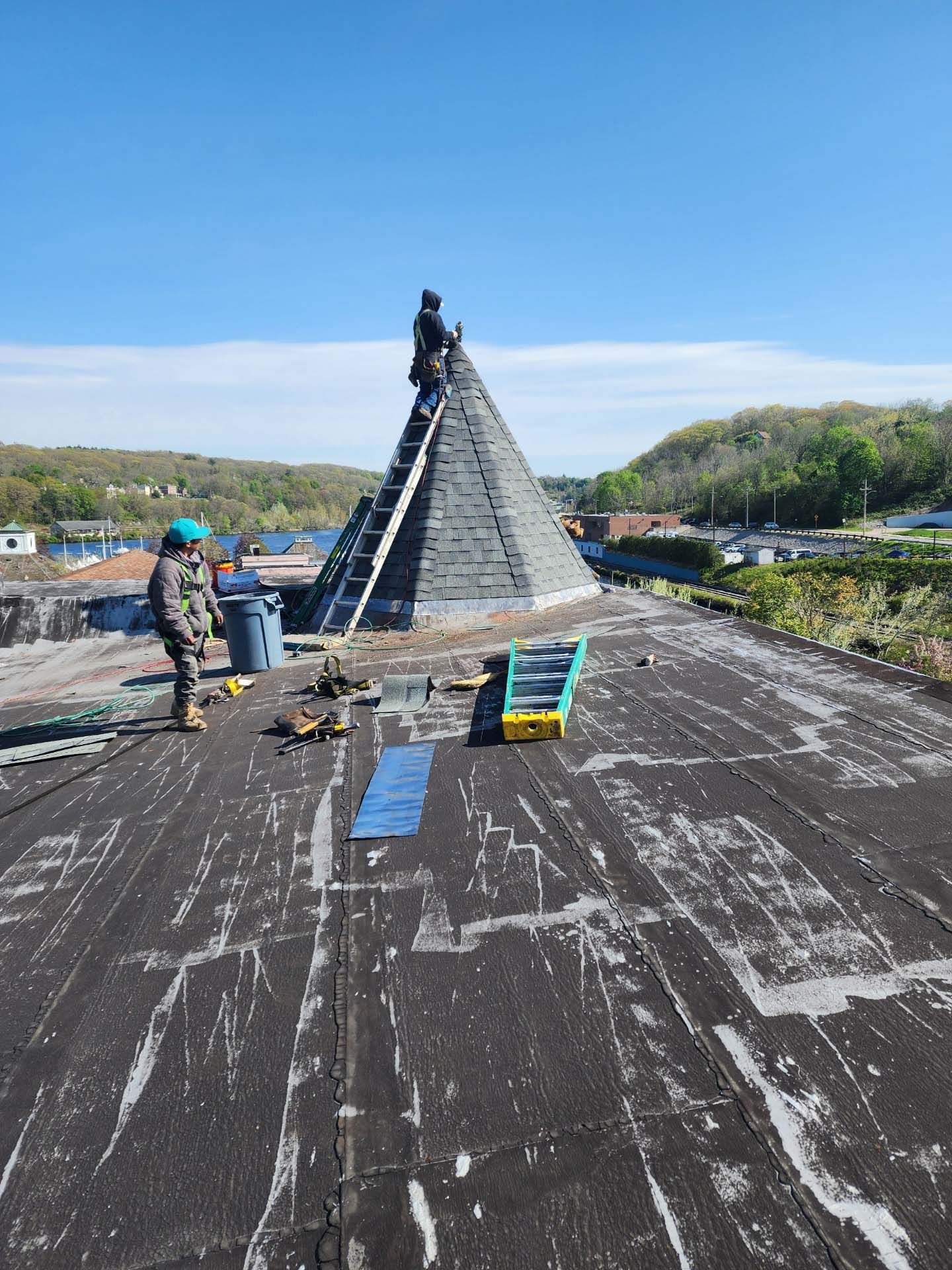 A man is standing on a roof next to a pyramid.