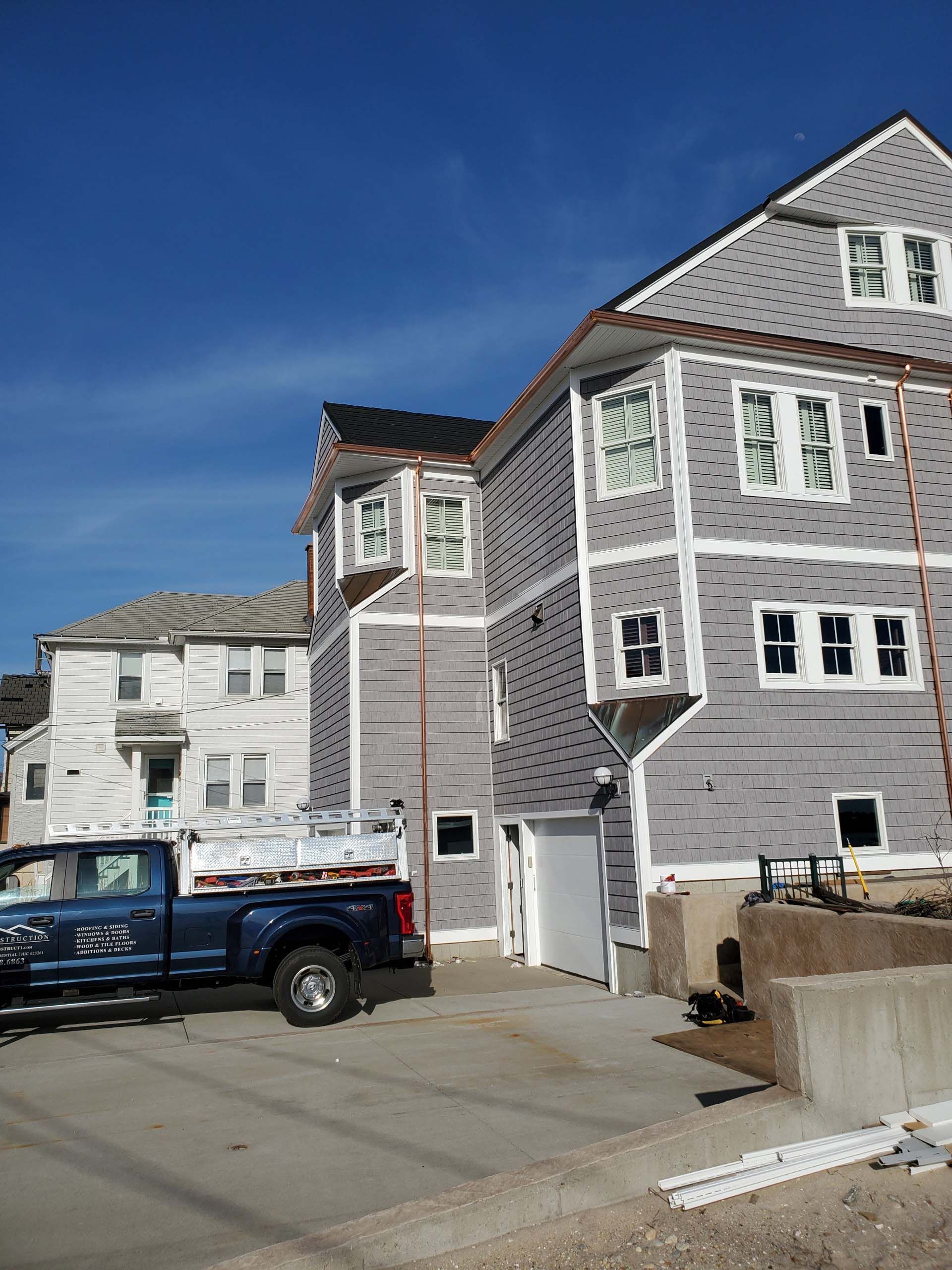 A blue truck is parked in front of a house under construction.