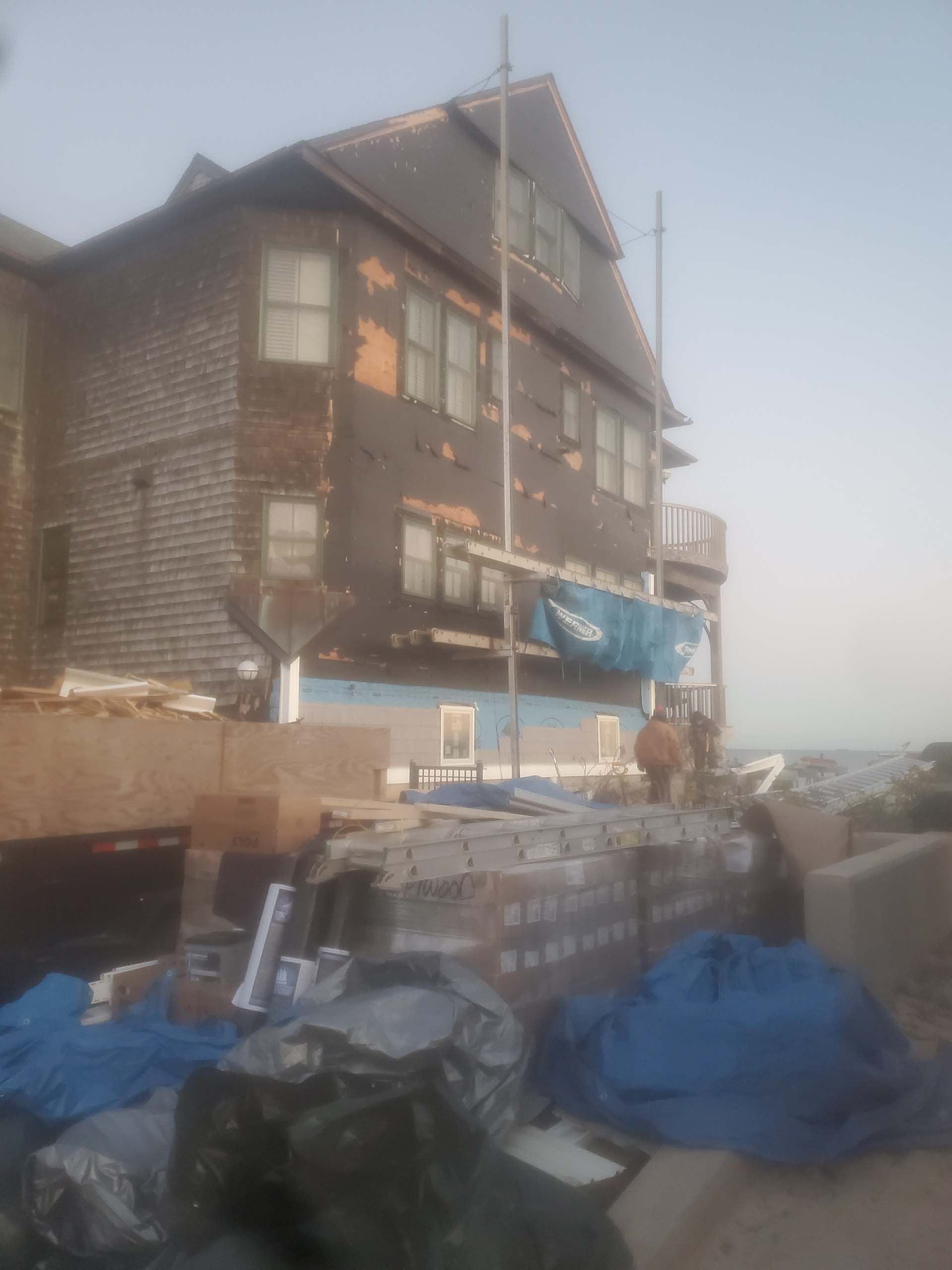 A large house with a blue tarp on the ground in front of it