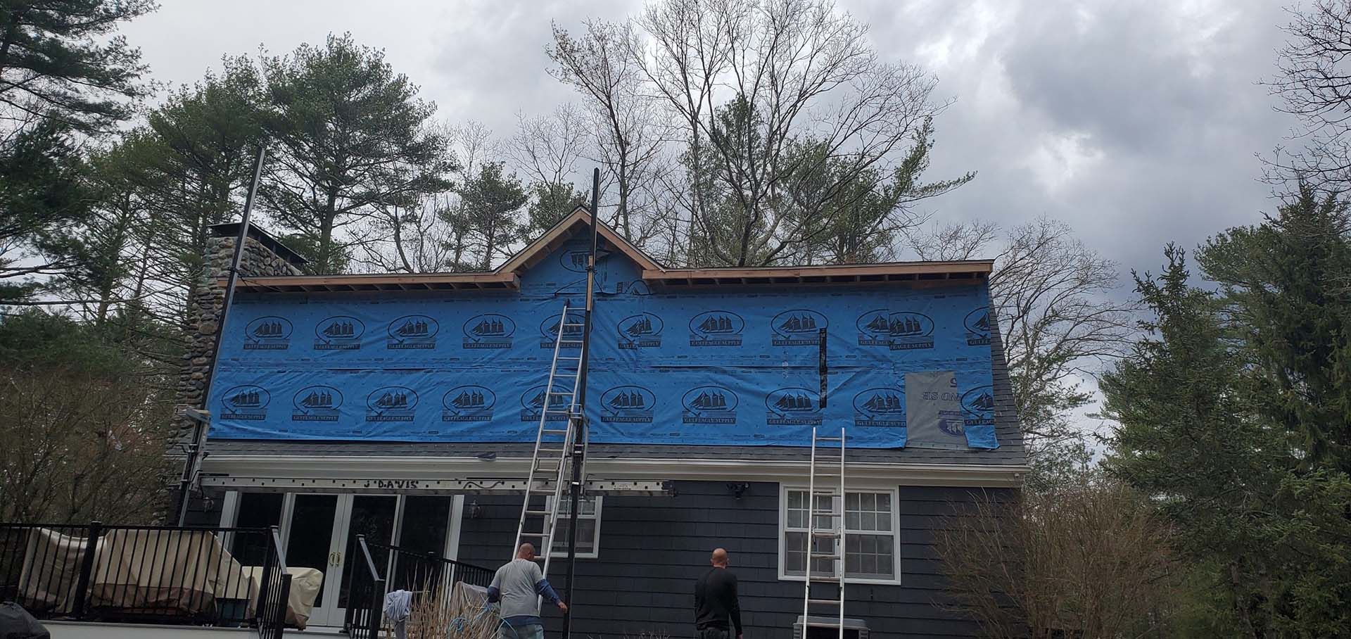 A house is being remodeled with a blue tarp on the roof.