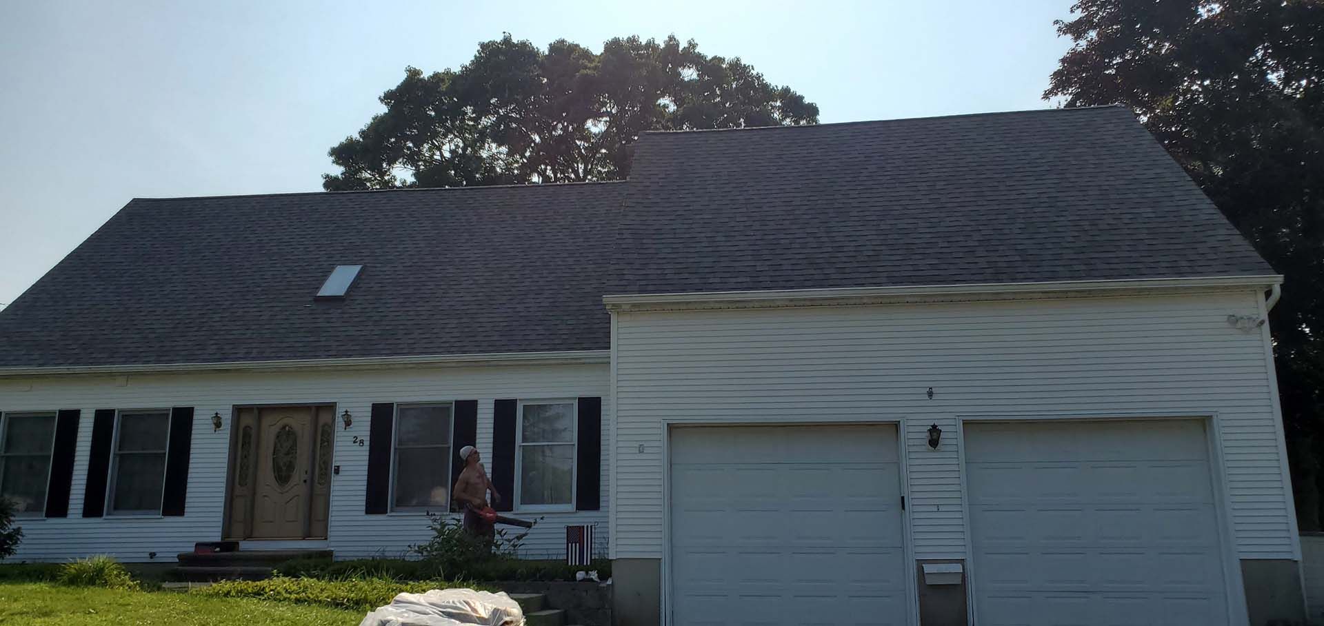 A white house with a gray roof and two garage doors