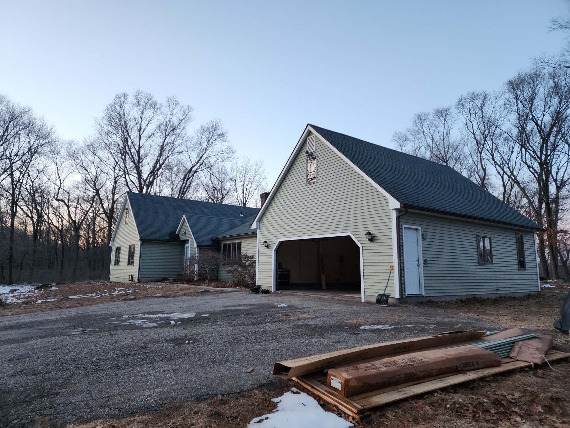 A garage with a blue roof is next to a house.