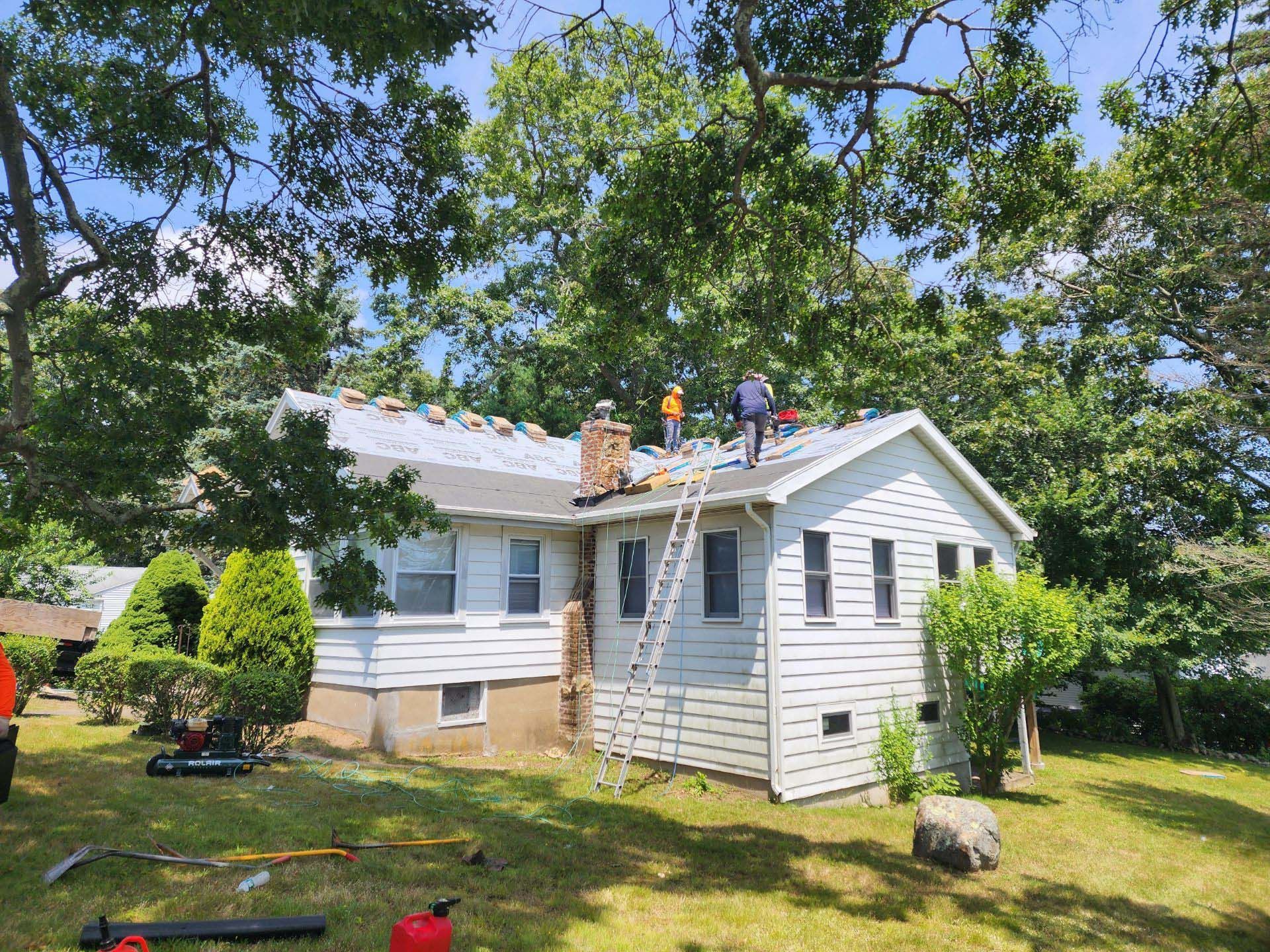 A group of people are working on the roof of a house.