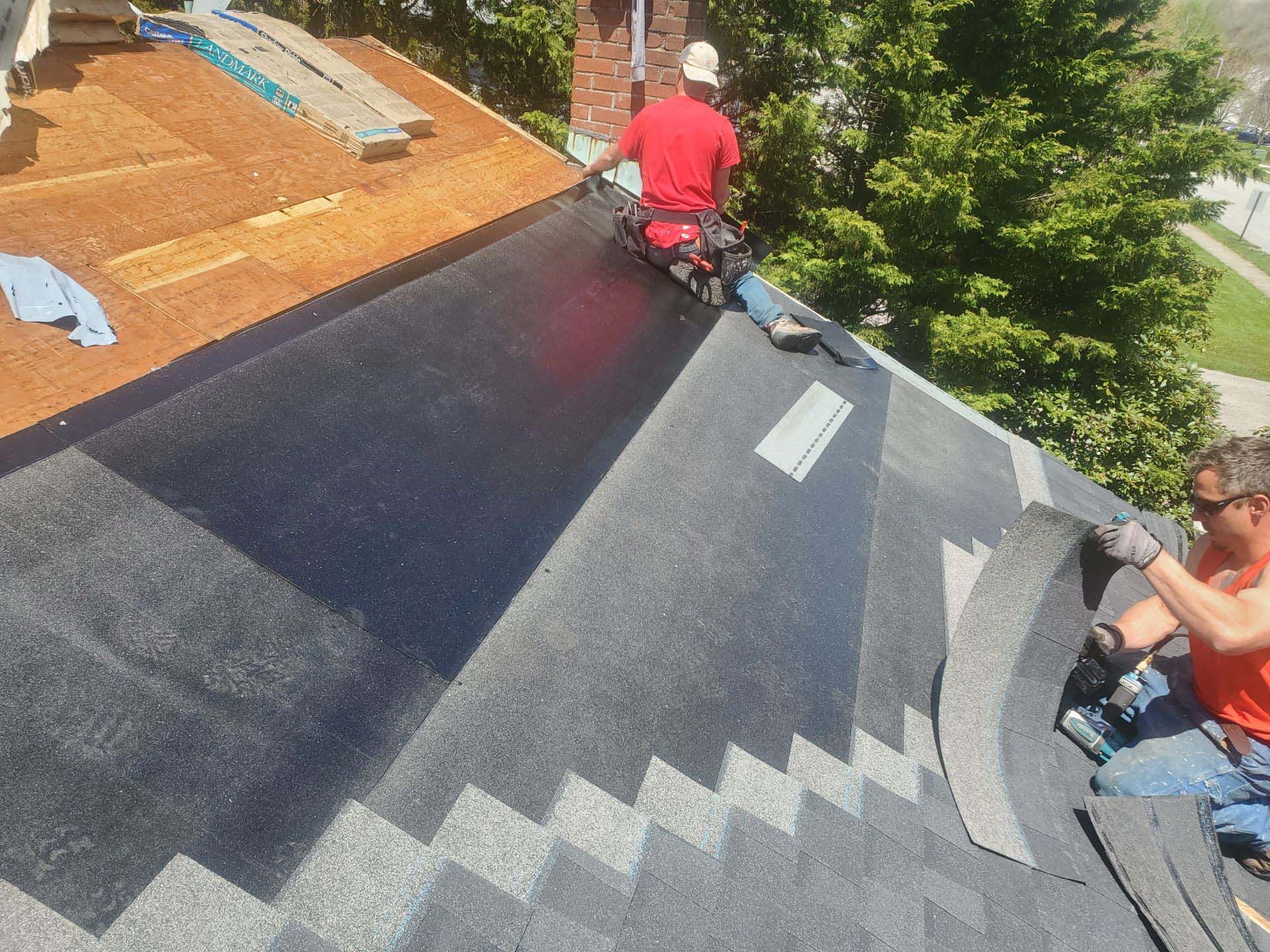 Two men are working on the roof of a house.