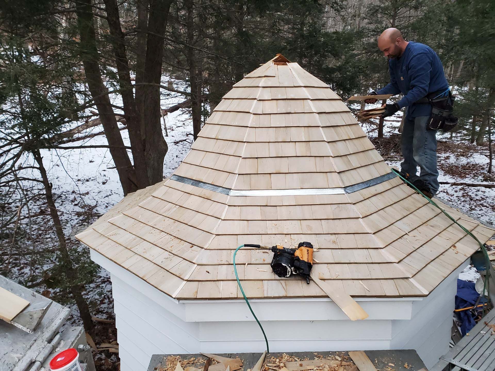 A man is working on a wooden roof in the snow