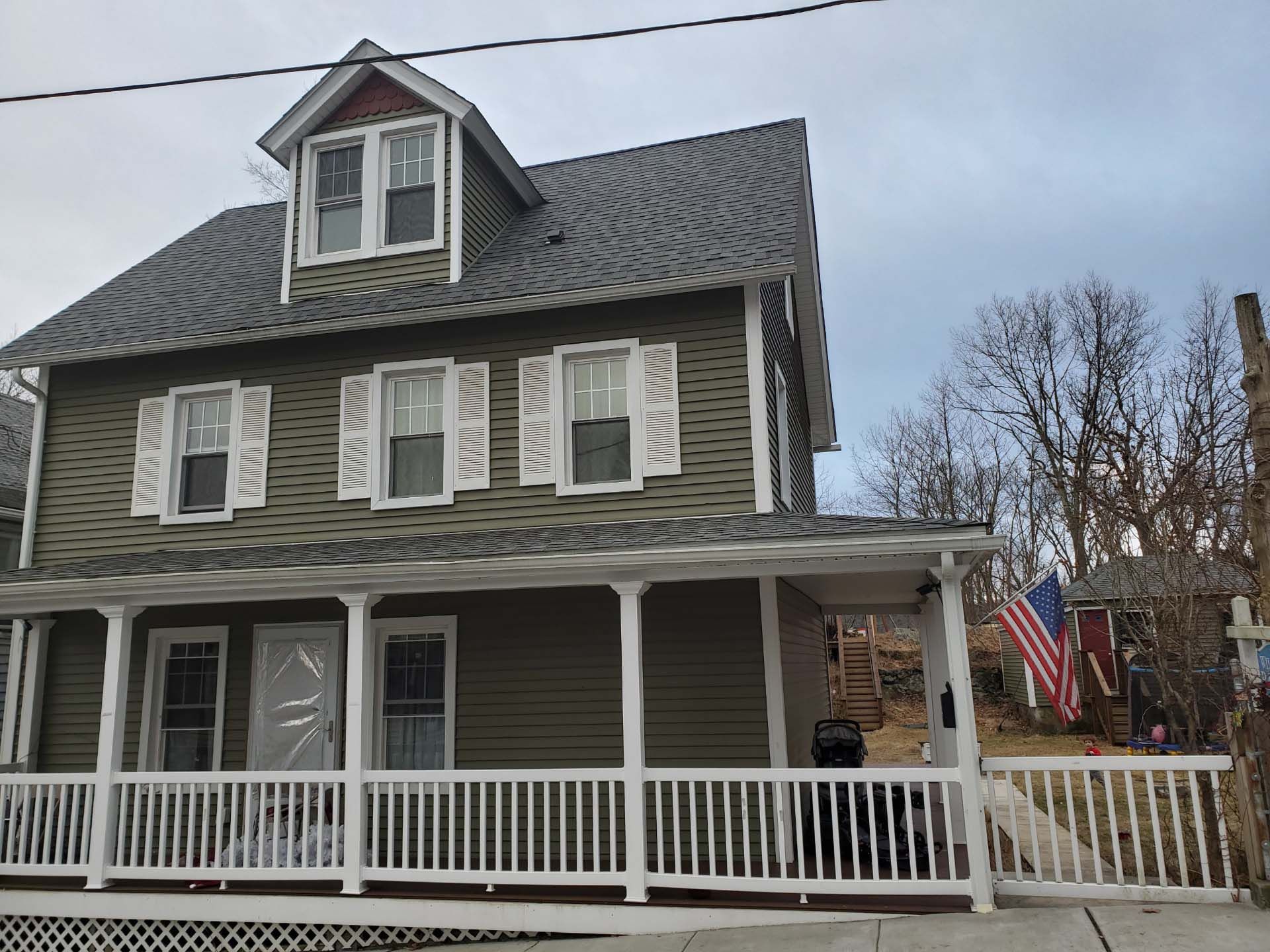 A green house with white shutters and a porch.