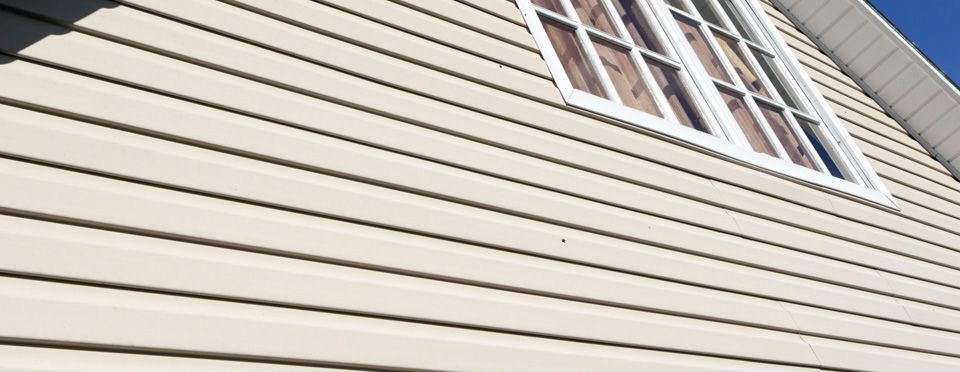 A close up of the side of a house with siding and windows.