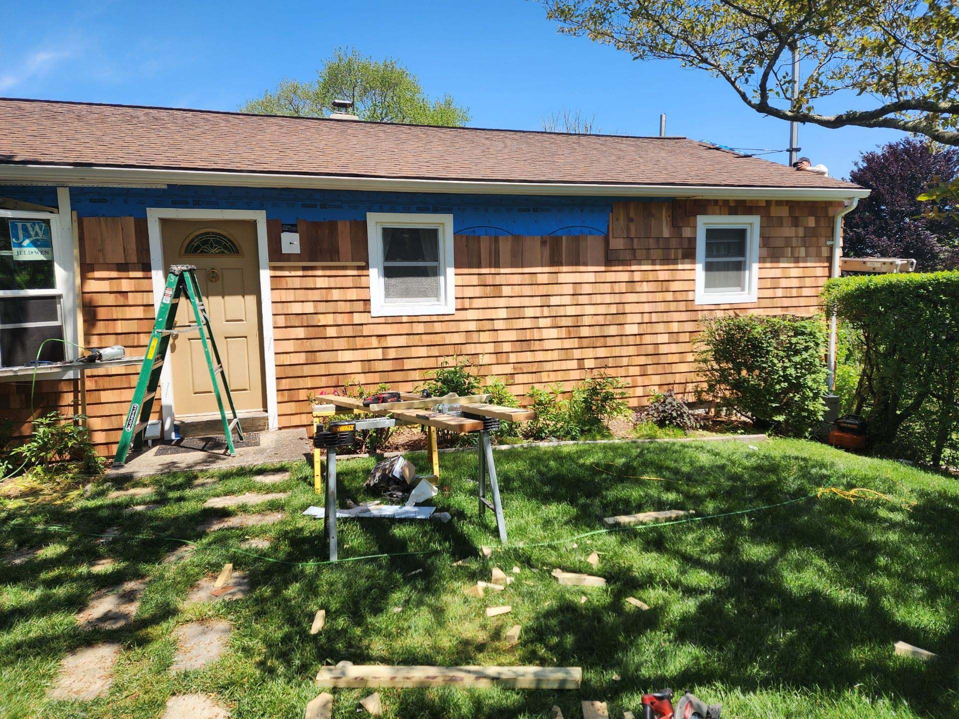 A house with a ladder in front of it is being painted blue.