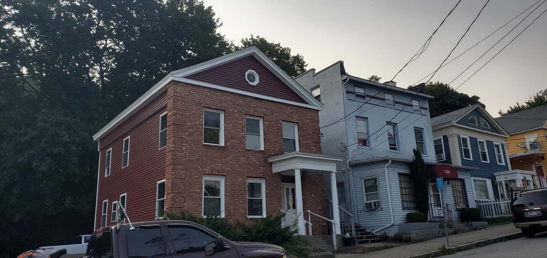 A brick building with a red roof is next to a white building.