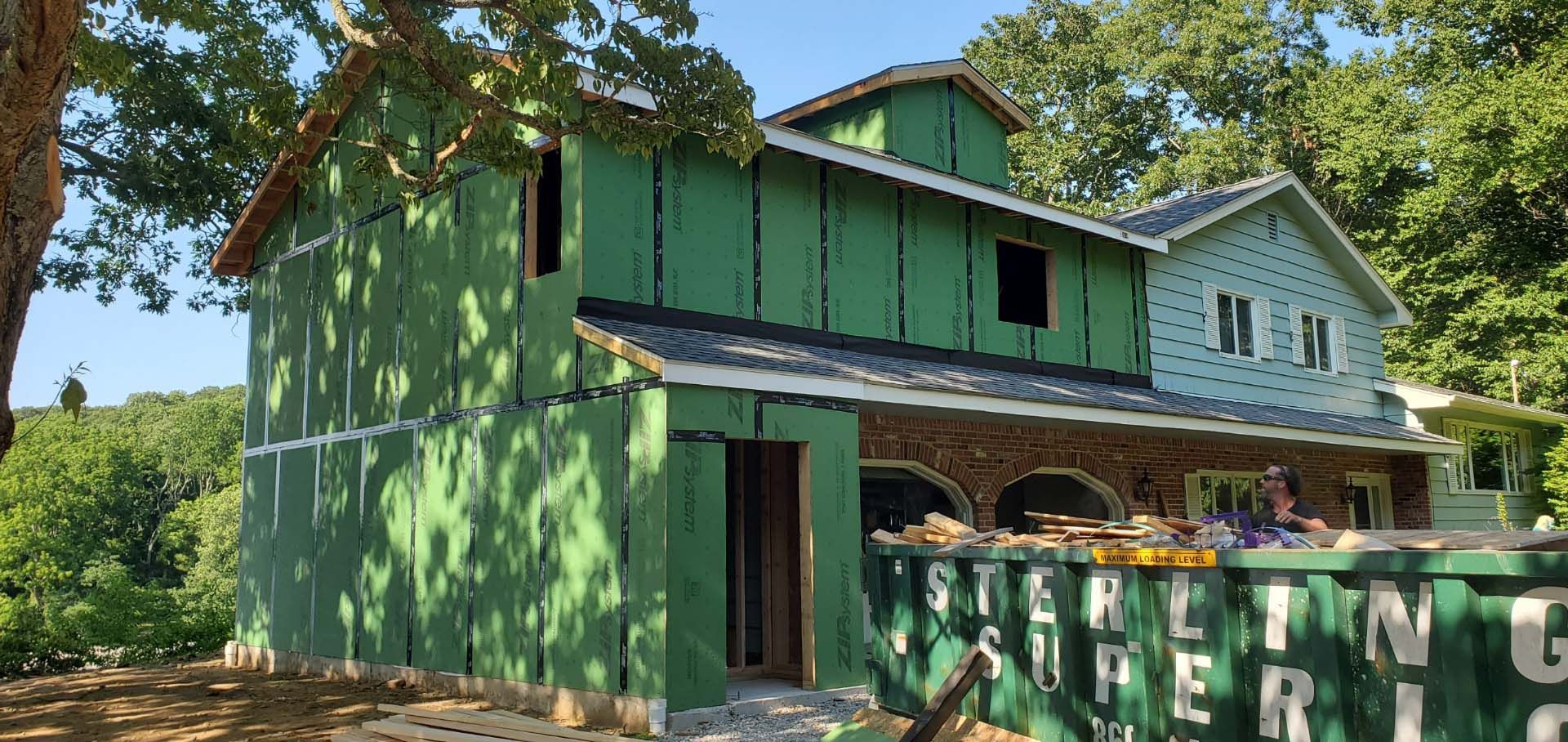 A large green house is being built in the middle of a forest.
