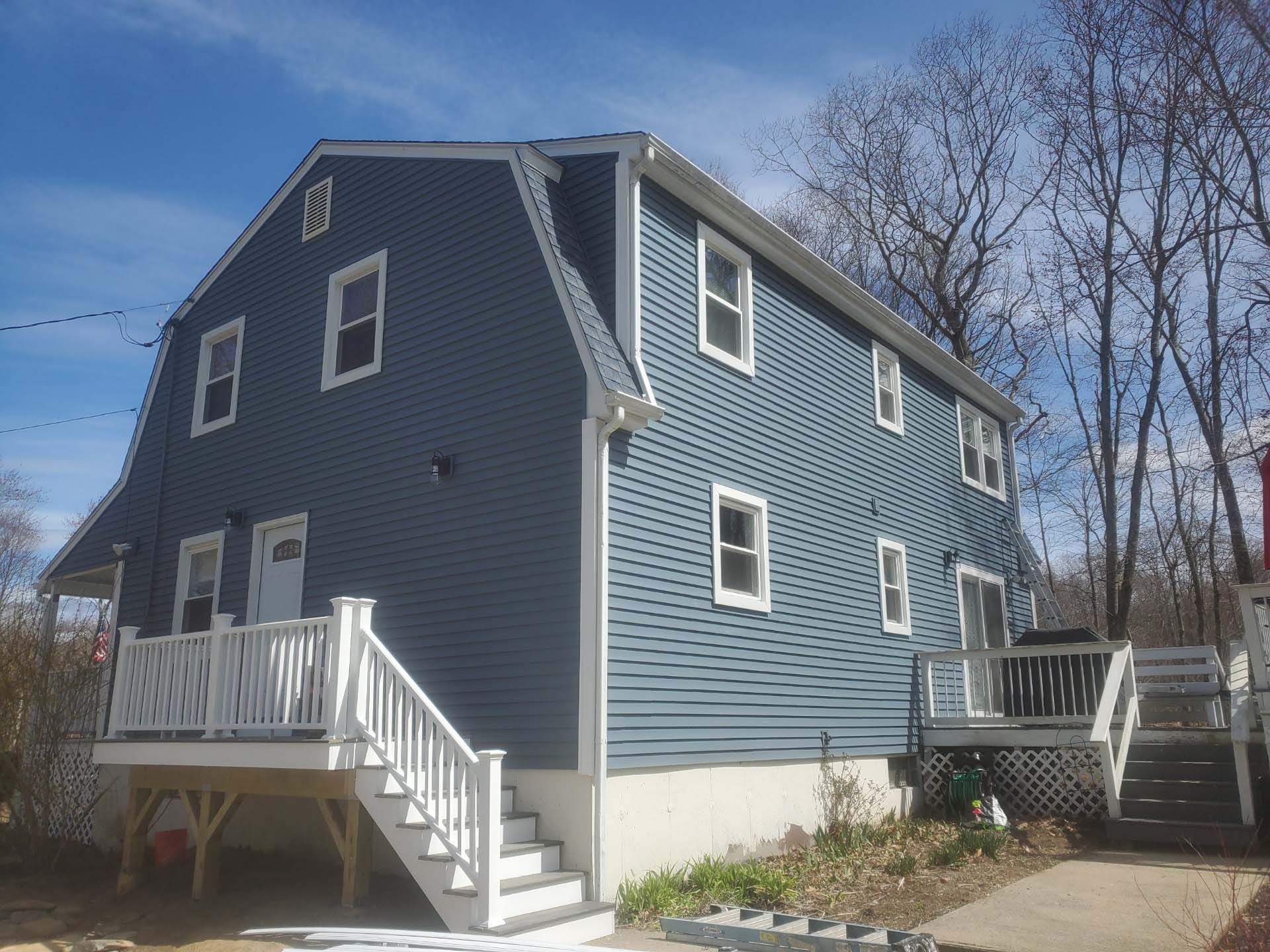 A blue house with a white deck and stairs