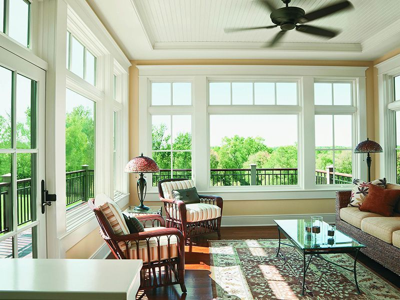 A living room with a lot of windows and a ceiling fan