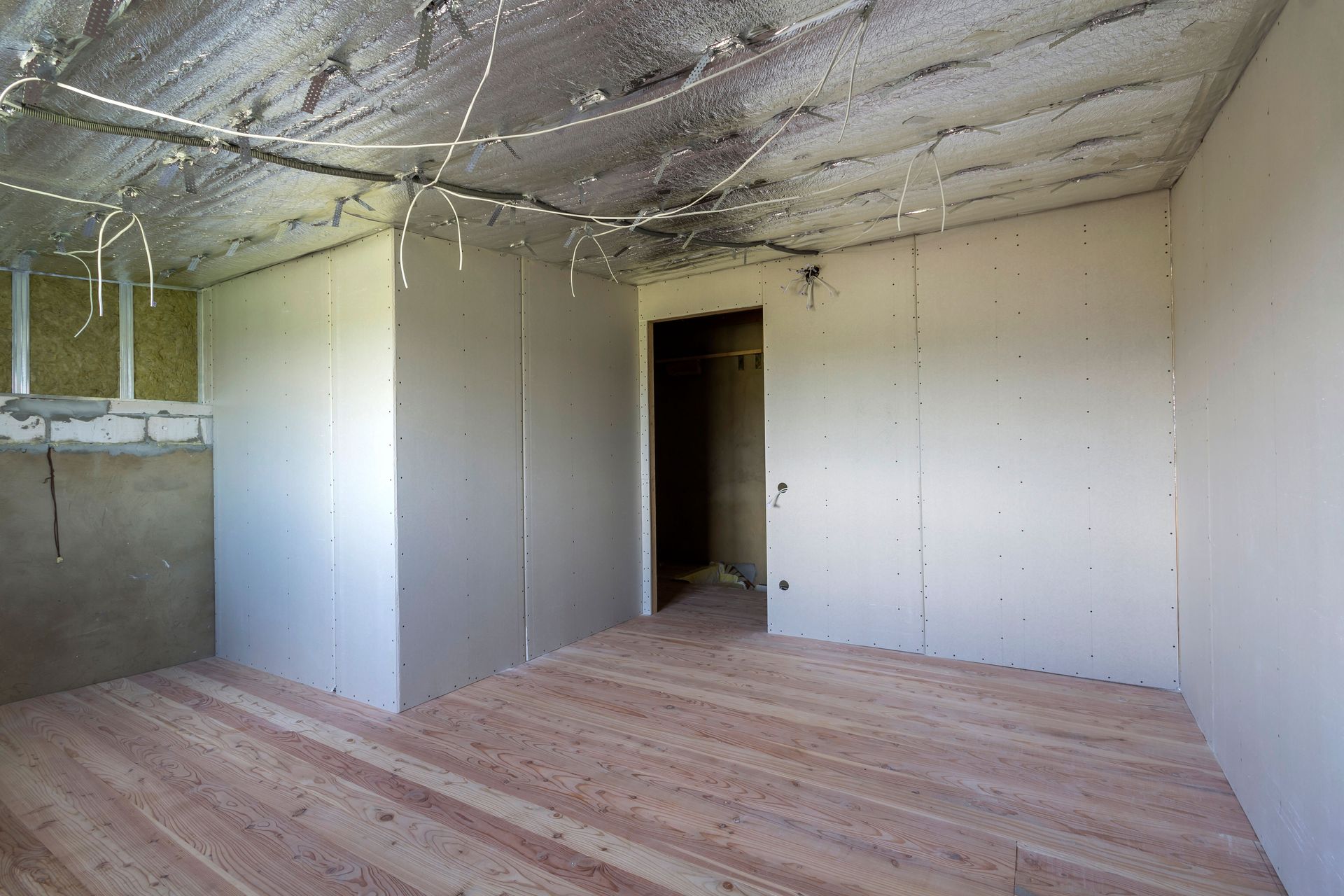 An empty room with wooden floors and drywall on the walls.
