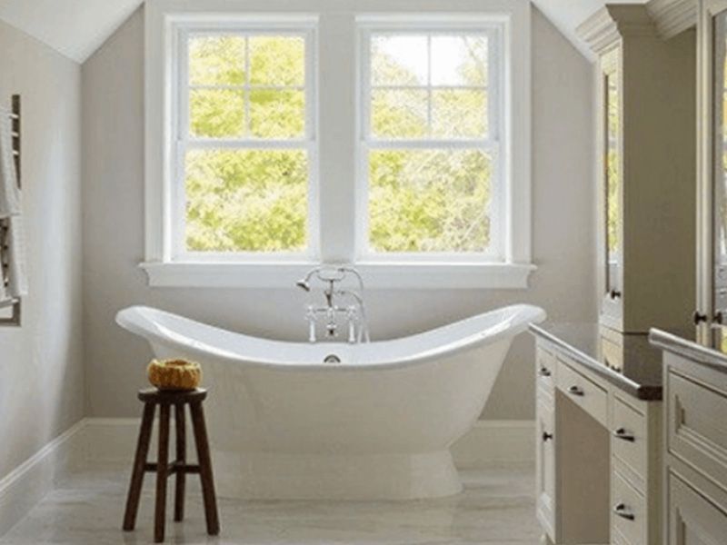 A bathroom with a bathtub and two windows