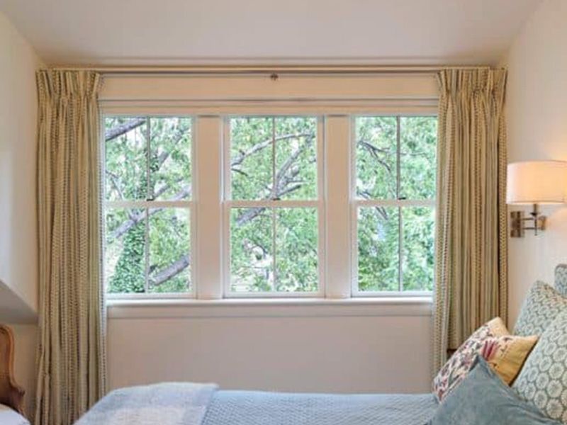 A bedroom with a large window and a bed.