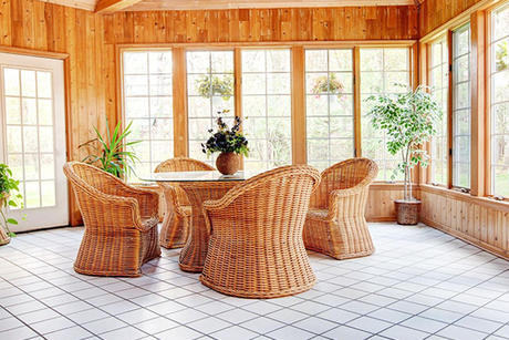There is a table and chairs in the sunroom with lots of windows.