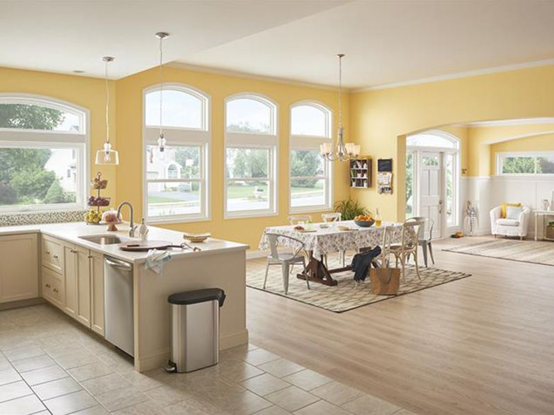 A kitchen with yellow walls and a dining room with a table and chairs.