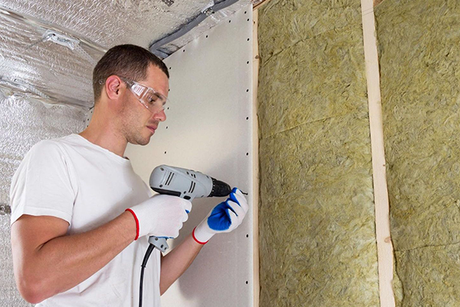 A man is using a drill on a wall.