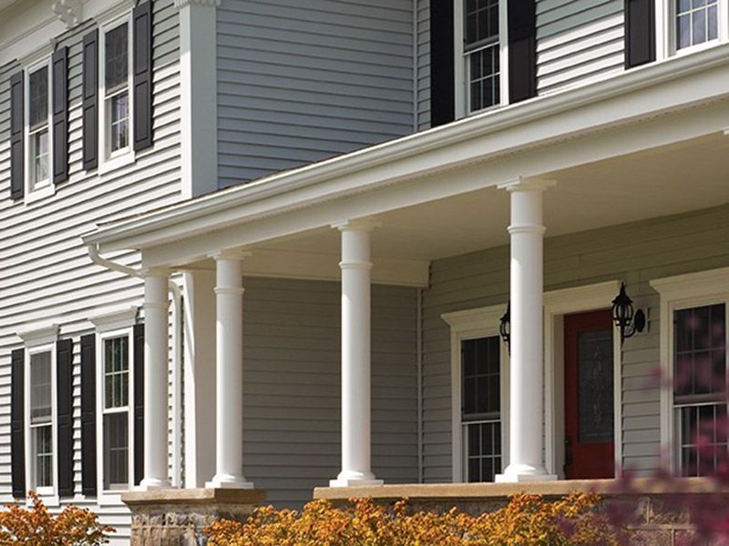 The front porch of a house with columns and a red door