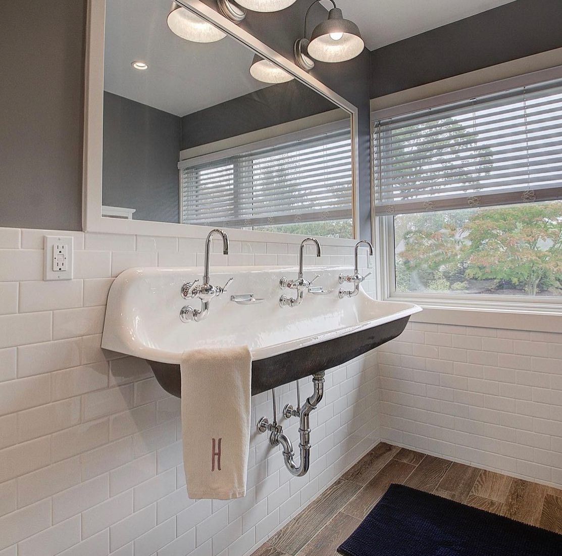 Bathroom with a large white sink, chrome faucets, and a towel. White subway tile, gray walls, and a window.