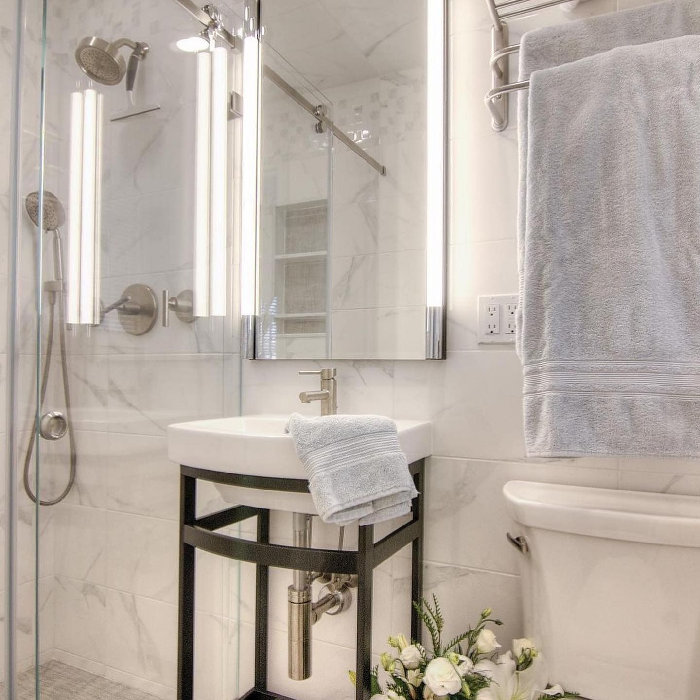 Modern white bathroom with sink, mirror, shower, and toilet.