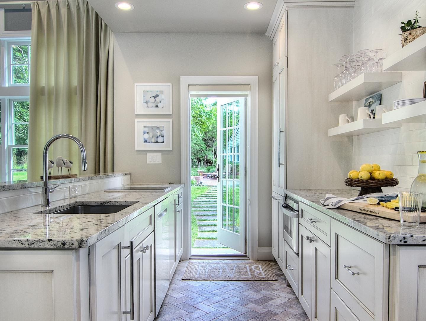 White kitchen with granite countertops, stainless steel sink, and French doors leading to a backyard.