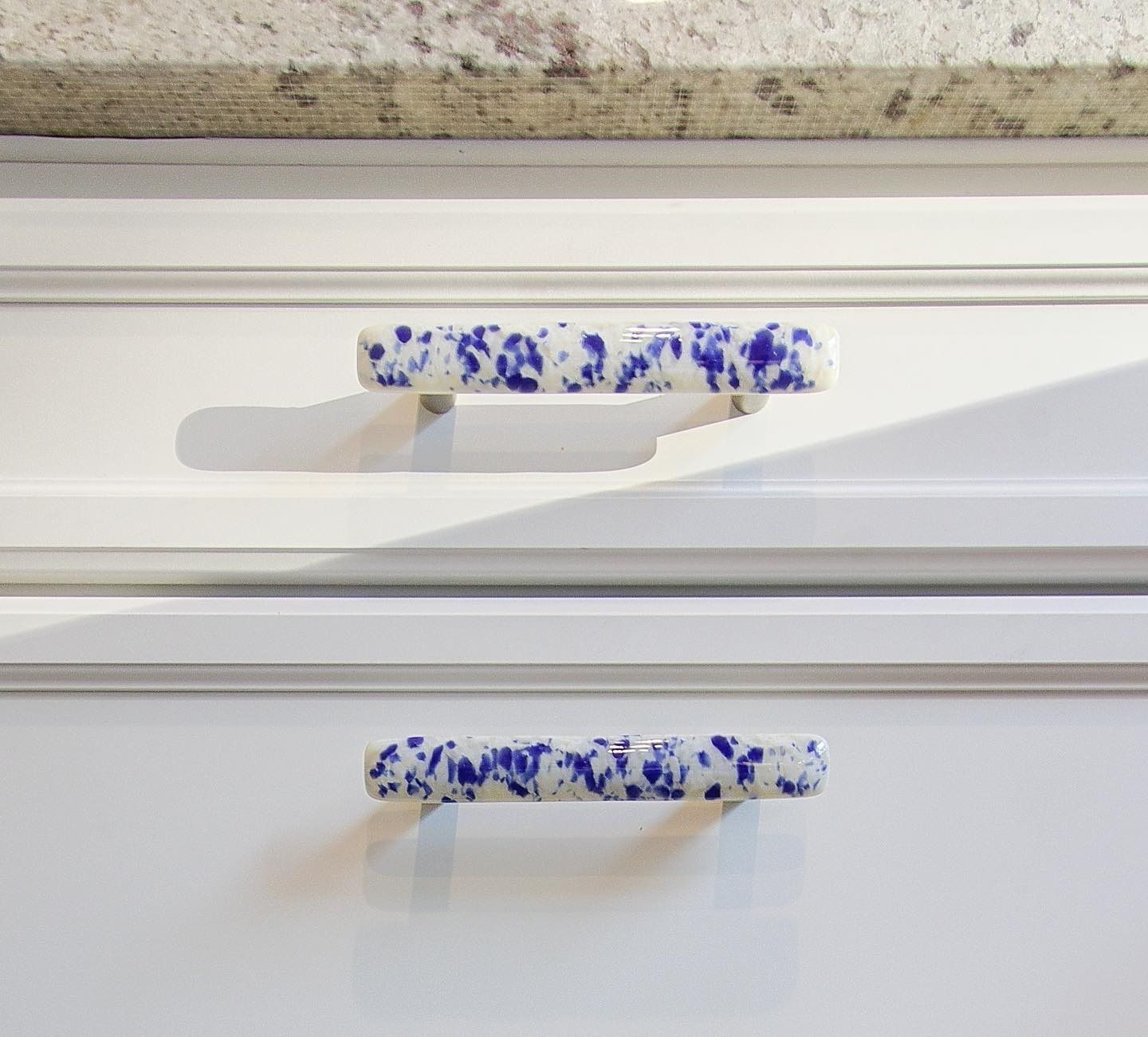 White kitchen cabinet drawers with blue speckled handles.