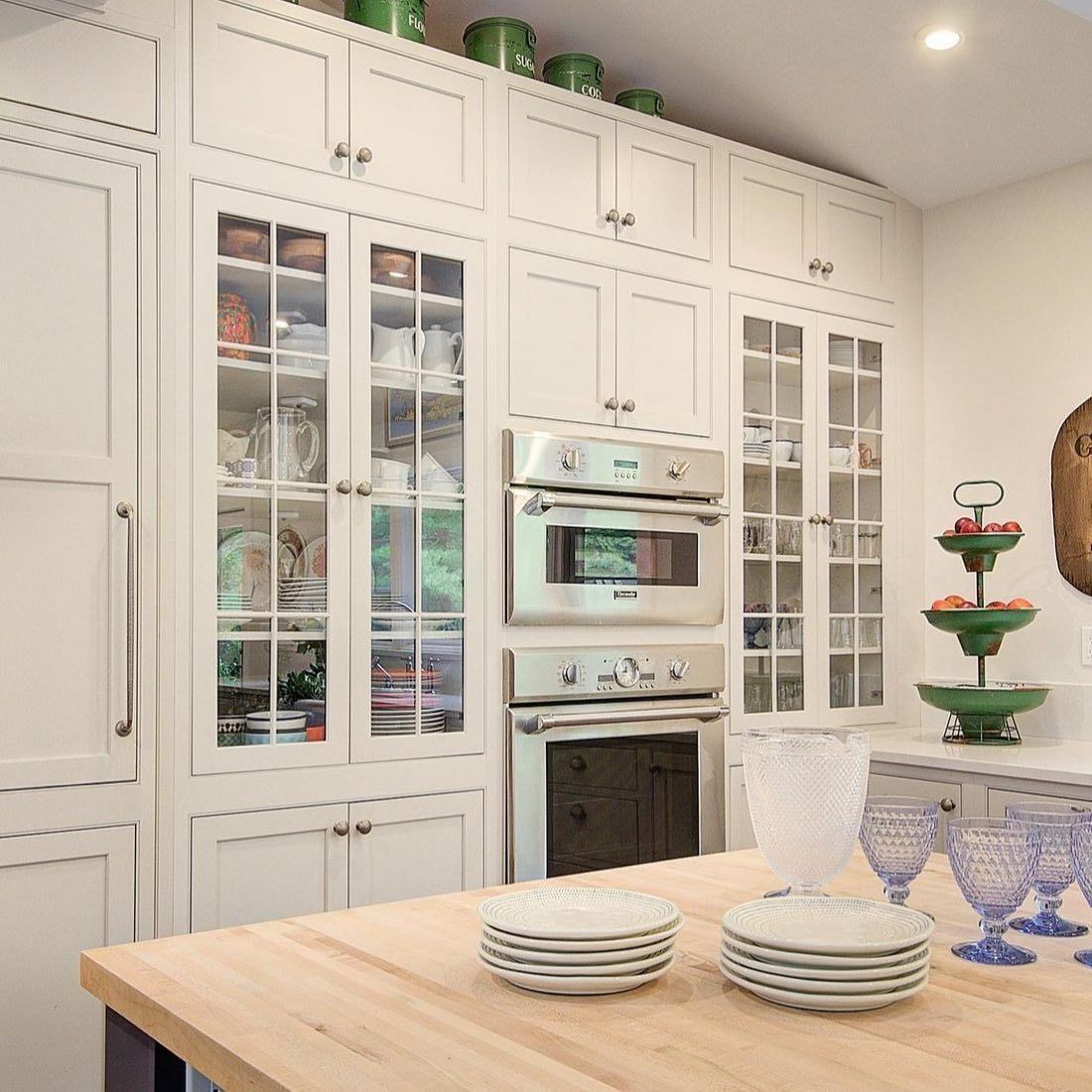 White kitchen with built-in cabinetry, glass-fronted cabinets, and a double oven.