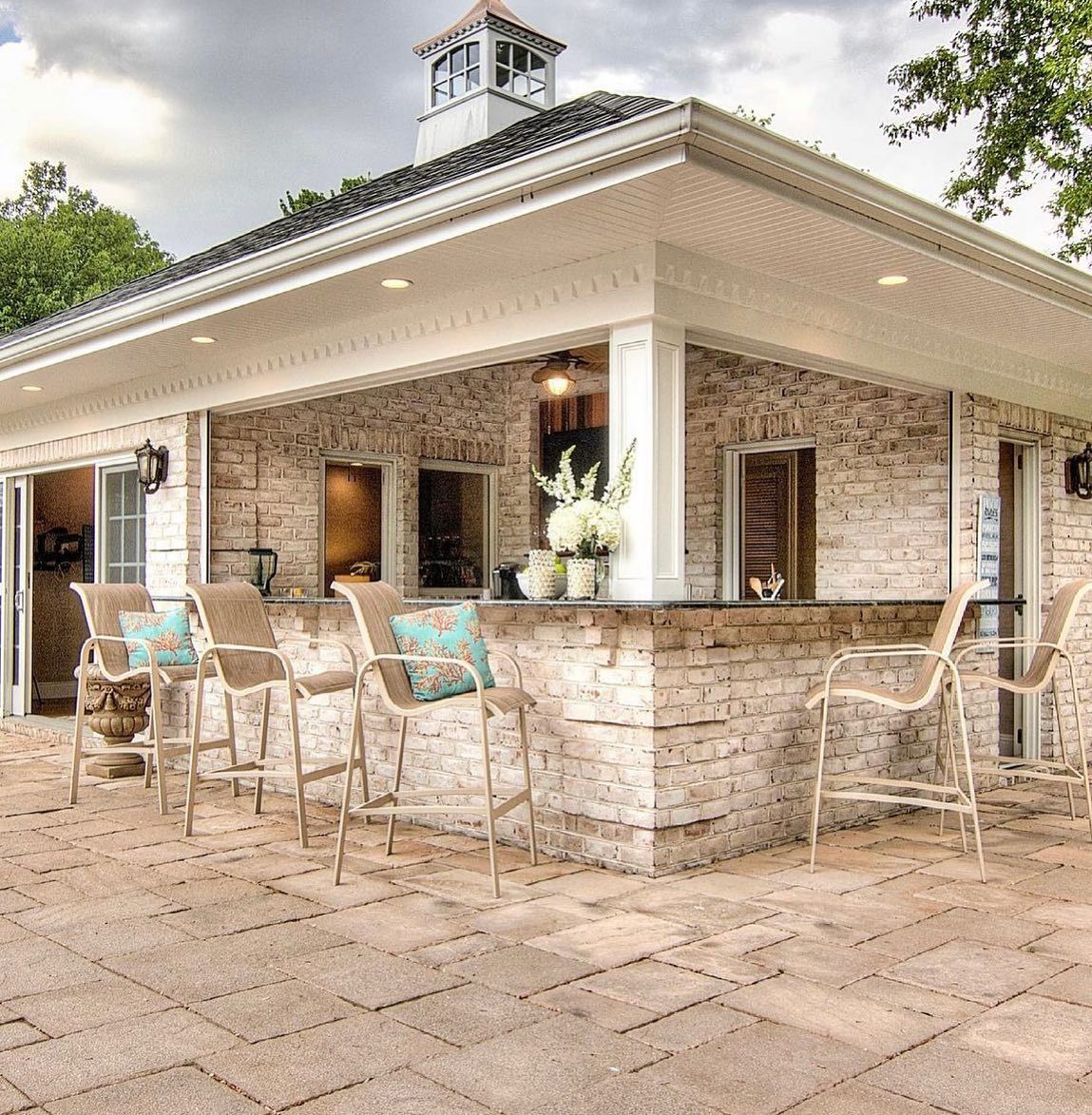 Outdoor bar with stone facade, bar stools, and a small cupola in a patio setting.