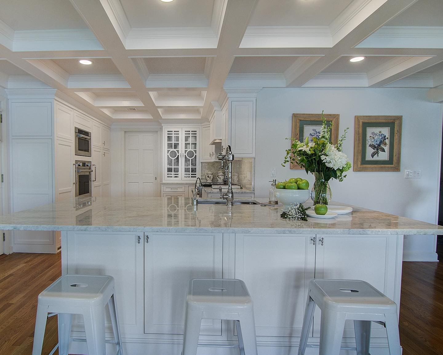 White kitchen with island, stools, and beamed ceiling.