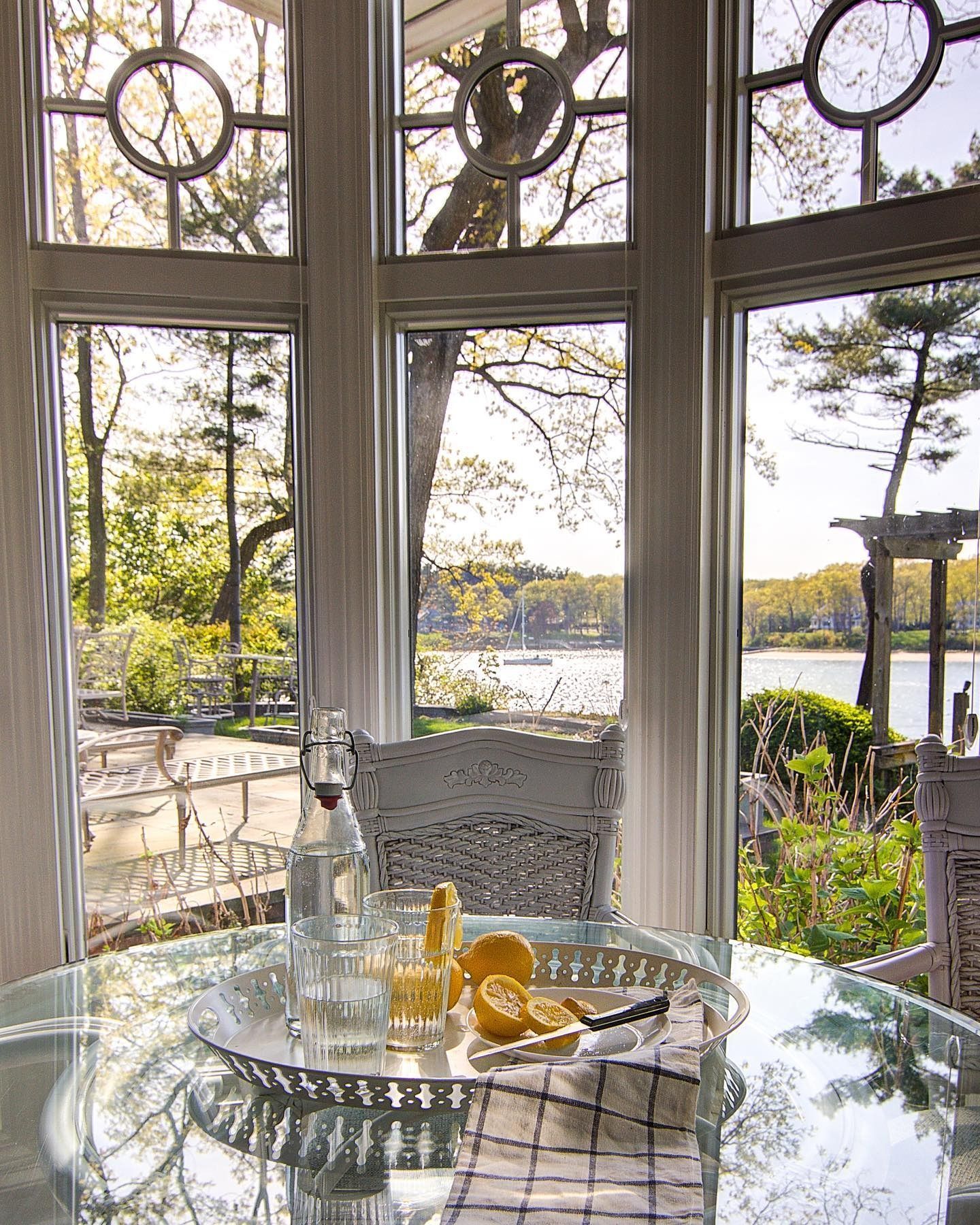 Table setting near windows overlooking a body of water. Tray with lemons and a carafe.