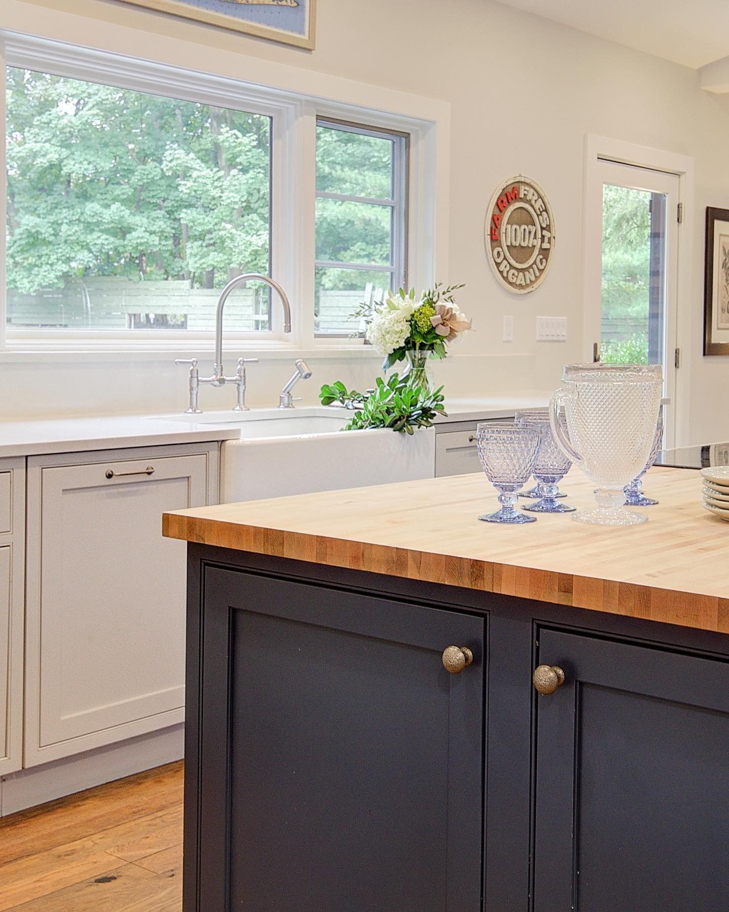 Kitchen with blue island, butcher block countertop, white cabinets, and large window.