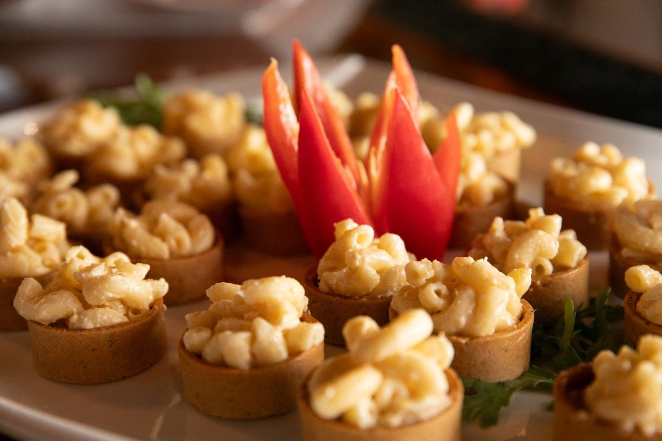 A plate of macaroni and cheese appetizers with a tomato on top.