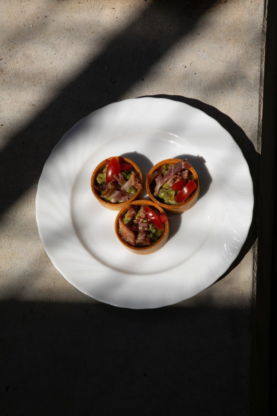 A white plate topped with three small plates of food on a table.