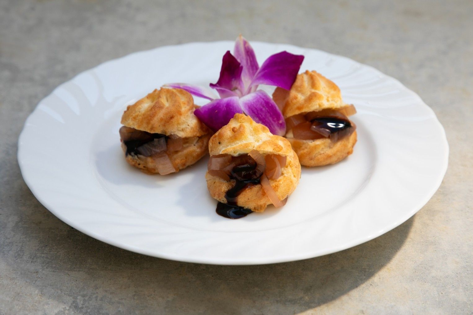 A plate of food with a purple flower on top