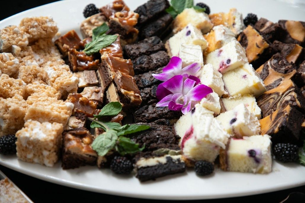 A white plate topped with a variety of desserts and flowers.