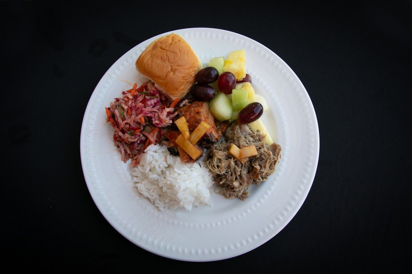 A white plate topped with a variety of food and fruit.